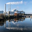 Industrial power plant with smokestacks reflecting in Hamburg river.